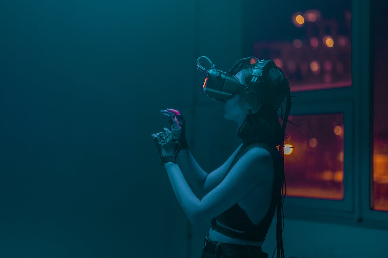 A woman wearing a VR headset and gloves immersed in a virtual reality experience inside a dimly lit room.